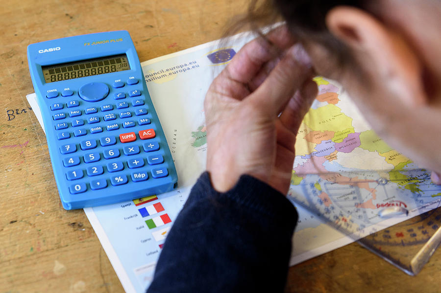 Um estudante com calculadora, mapa e transferidor.